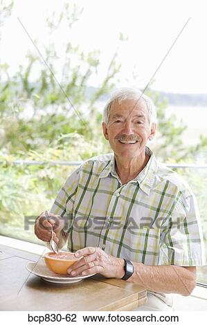 Stock Image - Man eating a grapefruit. Fotosearch