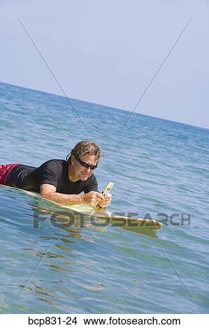 Man floating on water and text messaging View Large Photo Image Picture - Man floating on water and text messaging. Fotosearch