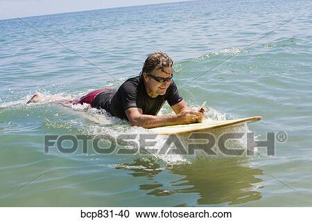 Stock Image - Man floating on water and text messaging. Fotosearch