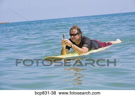 Stock Photo - Man floating on water and text messaging. Fotosearch