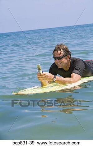 Man floating on water and text messaging View Large Photo Image Stock Photo - Man floating on water and text messaging. Fotosearch