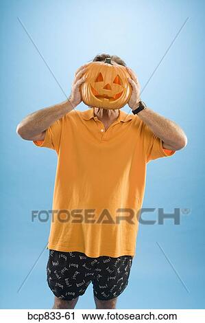 Man hiding his face with a Jack O' Lantern View Large Photo Image Stock Image - Man hiding his face with a Jack O' Lantern. Fotosearch