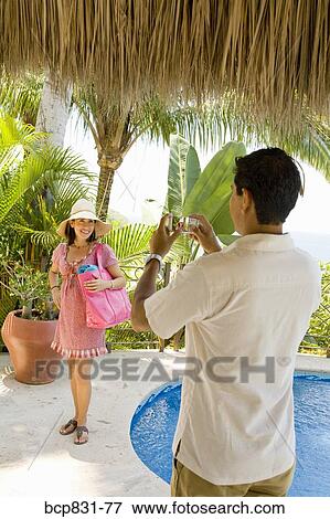 Stock Photo - Man photographing his wife at the poolside. Fotosearch