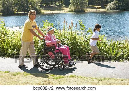 Man pushing his mother sitting in a wheelchair View Large Photo Image Stock Image - Man pushing his mother sitting in a wheelchair. Fotosearch