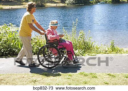Man pushing his mother sitting in a wheelchair View Large Photo Image Stock Image - Man pushing his mother sitting in a wheelchair. Fotosearch