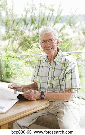 Stock Image - Man reading a magazine and smiling. Fotosearch
