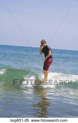 Stock Photograph - Man surfing and talking on the phone. Fotosearch