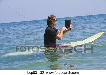 Stock Image - Man surfing and using a laptop. Fotosearch