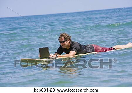 Man surfing and using a laptop View Large Photo Image Stock Photo - Man surfing and using a laptop. Fotosearch