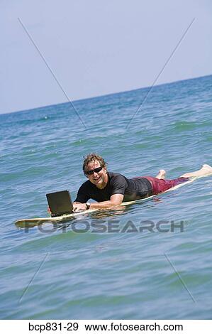 Man surfing and using a laptop View Large Photo Image Stock Photo - Man surfing and using a laptop. Fotosearch