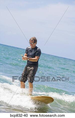 Man surfing in the sea and using a mobile phone View Large Photo Image Stock Image - Man surfing in the sea and using a mobile phone. Fotosearch