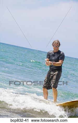 Man surfing in the sea and using a mobile phone View Large Photo Image Stock Image - Man surfing in the sea and using a mobile phone. Fotosearch