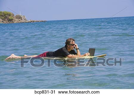 Man talking on a phone and using a laptop in the sea View Large Photo Image Stock Image - Man talking on a phone and using a laptop in the sea. Fotosearch