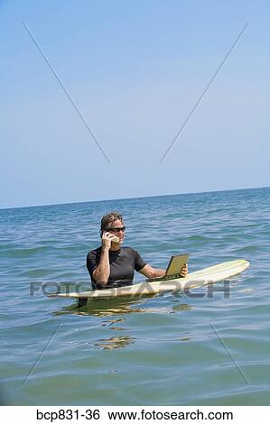 Man talking on a phone and using a laptop in the sea View Large Photo Image Stock Photograph - Man talking on a phone and using a laptop in the sea. Fotosearch