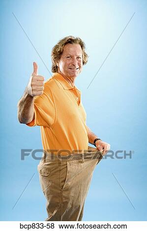 Stock Photo - Man wearing loose pants and gesturing thumbs up sign. Fotosearch