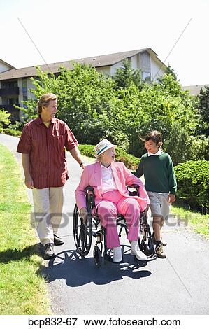 Man with a girl assisting a woman in a wheelchair View Large Photo Image Stock Photo - Man with a girl assisting a woman in a wheelchair. Fotosearch
