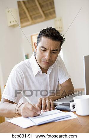 Stock Image - Man working on a laptop and preparing home finance budget. Fotosearch