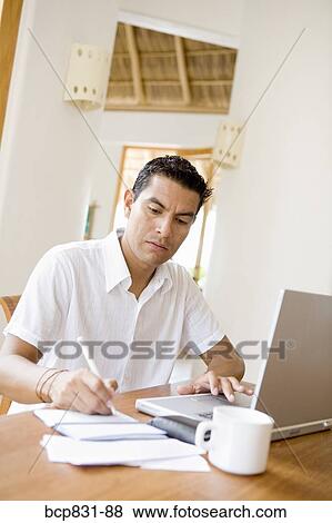Man working on a laptop and preparing home finance budget View Large Photo Image Stock Photo - Man working on a laptop and preparing home finance budget. Fotosearch