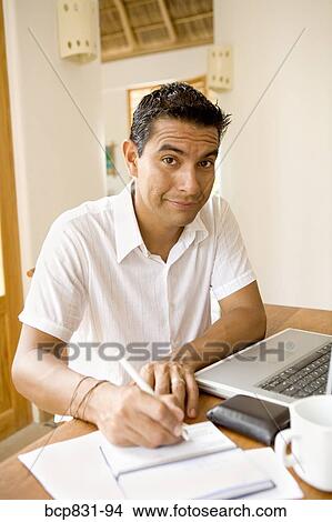 Picture - Portrait of a man signing a check and preparing home finance budget. Fotosearch