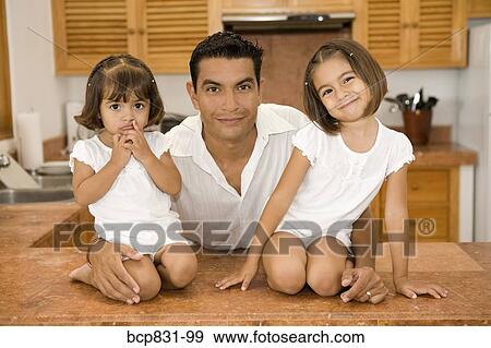 Stock Photo - Portrait of a man with his daughters in the kitchen. Fotosearch