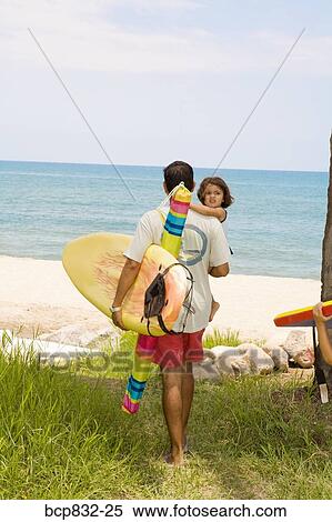 Rear view of a man carrying his daughter on the beach View Large Photo Image Stock Photography - Rear view of a man carrying his daughter on the beach. Fotosearch