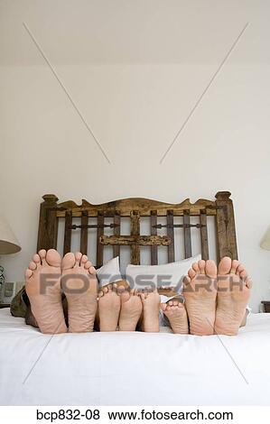 Soles of couple's and their children's feet on the bed View Large Photo Image Stock Photo - Soles of couple's and their children's feet on the bed. Fotosearch