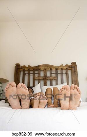 Soles of couple's and their children's feet on the bed View Large Photo Image Stock Photo - Soles of couple's and their children's feet on the bed. Fotosearch
