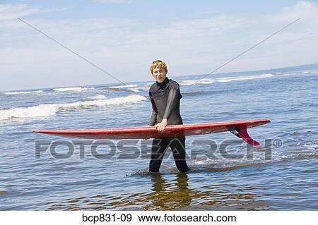 Surfer carrying a surfboard in water, Washington State, USA View Large Photo Image Stock Photo - Surfer carrying a surfboard in water, Washington State, USA. Fotosearch