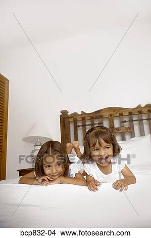 Two girls lying on the bed View Large Photo Image Picture - Two girls lying on the bed. Fotosearch