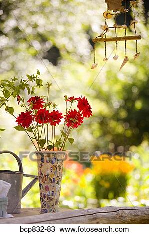Watering can with a vase of flowers and a wind chime View Large Photo Image Stock Image - Watering can with a vase of flowers and a wind chime. Fotosearch