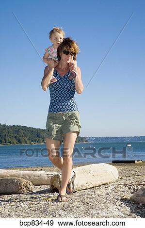 Woman carrying her daughter on her shoulders View Large Photo Image Stock Photo - Woman carrying her daughter on her shoulders. Fotosearch