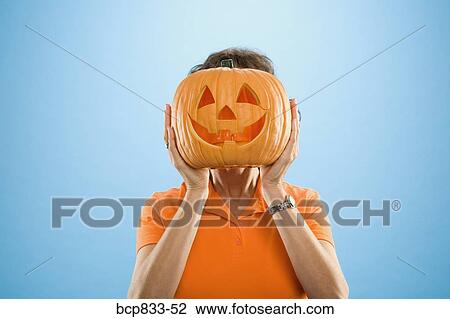 Woman covering her face with a Jack O' Lantern View Large Photo Image Stock Image - Woman covering her face with a Jack O' Lantern. Fotosearch