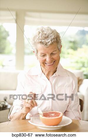 Stock Photo - Woman eating a grapefruit. Fotosearch