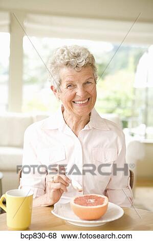 Stock Photo - Woman eating a grapefruit. Fotosearch
