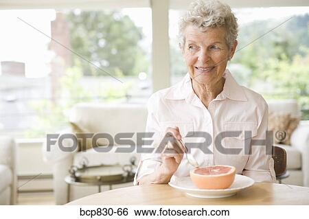 Stock Photograph - Woman eating a grapefruit. Fotosearch