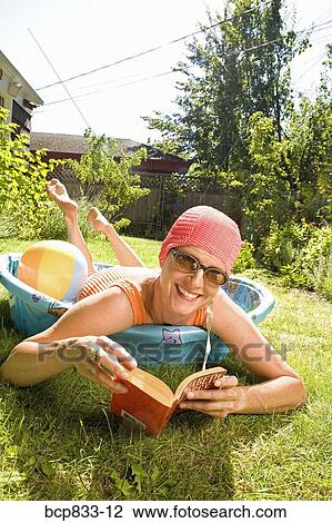 Stock Image - Woman holding a book in a wading pool. Fotosearch