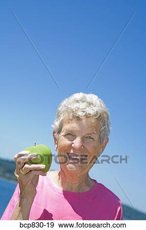 Stock Photo - Woman holding an apple. Fotosearch