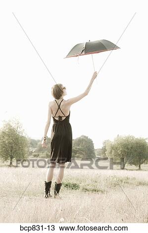 Woman holding an umbrella in a field View Large Photo Image Stock Image - Woman holding an umbrella in a field. Fotosearch