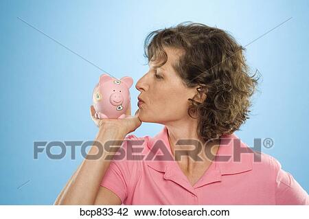 Stock Image - Woman kissing a piggy bank. Fotosearch