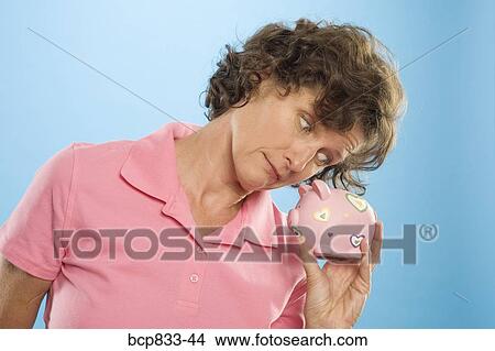 Woman looking into a piggy bank View Large Photo Image Picture - Woman looking into a piggy bank. Fotosearch