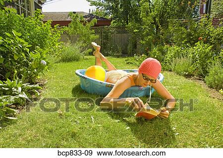Woman lying in a wading pool and reading a book View Large Photo Image Stock Photo - Woman lying in a wading pool and reading a book. Fotosearch