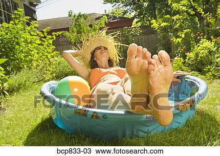 Stock Image - Woman lying in a wading pool. Fotosearch