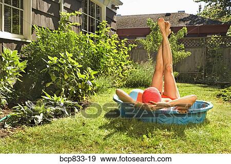 Stock Photo - Woman lying in a wading pool with her feet up. Fotosearch
