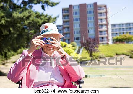 Woman photographing with a digital camera in a garden View Large Photo Image Picture - Woman photographing with a digital camera in a garden. Fotosearch