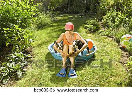 Woman reading a book in a wading pool between two Boston Terriers View Large Photo Image Stock Photography - Woman reading a book in a wading pool between two Boston Terriers. Fotosearch