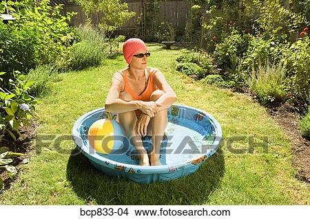 Picture - Woman sitting in a wading pool. Fotosearch
