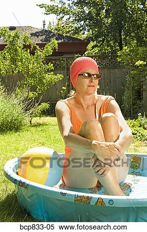 Stock Photography - Woman sitting in a wading pool. Fotosearch