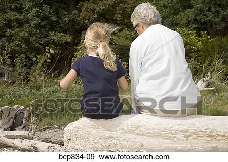 Woman sitting on a rock with her granddaughter View Large Photo Image Stock Photo - Woman sitting on a rock with her granddaughter. Fotosearch