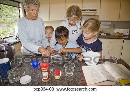 Woman teaching cooking to her grandchildren in the kitchen View Large Photo Image Stock Photo - Woman teaching cooking to her grandchildren in the kitchen. Fotosearch