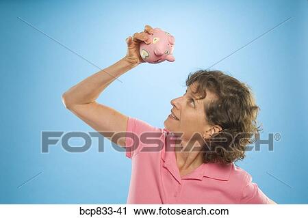 Woman trying to get money out of a piggy bank View Large Photo Image Stock Image - Woman trying to get money out of a piggy bank. Fotosearch